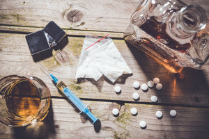 Overhead shot of hard drugs and alcohol on wooden table.